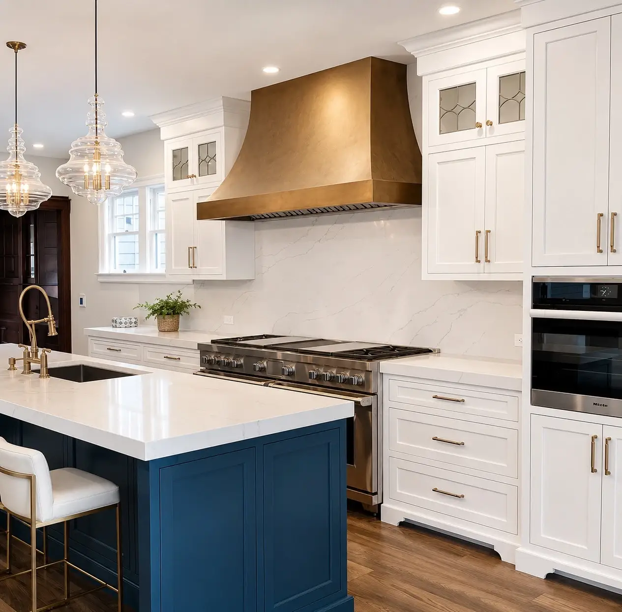 Luxury kitchen featuring a blue island with white countertop, white cabinetry, bronze range hood, stainless steel appliances, and crystal pendant lights.
