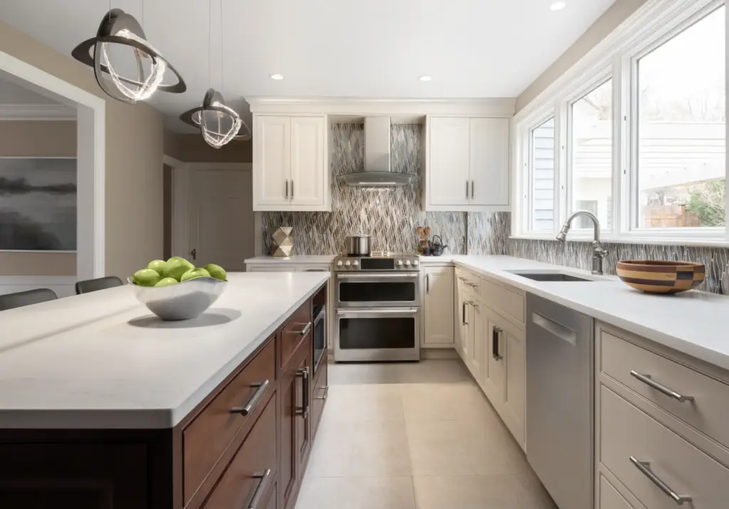 A contemporary kitchen features white cabinetry, a two-tone island with white and wood finishes, stainless steel double oven, mosaic tile backsplash, and pendant lighting overhead.